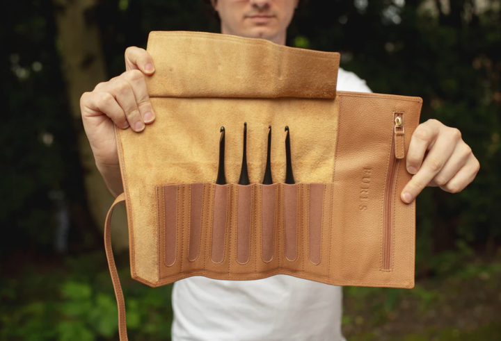 Venture & Tempest: A Furls Crochet Giveaway! This is a picture of an unrolled Leather Hook Pouch held open by a person. There are 4 hooks sticking out of the pockets of the pouch. 