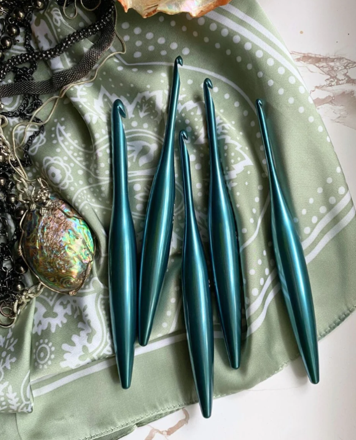Venture & Tempest: A Furls Crochet Giveaway! This is a picture of 5 blue crochet hooks scattered on a tablecloth.